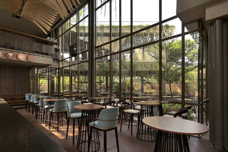 Dining area with floor-to-ceiling steel-framed glazing overlooking a planted courtyard