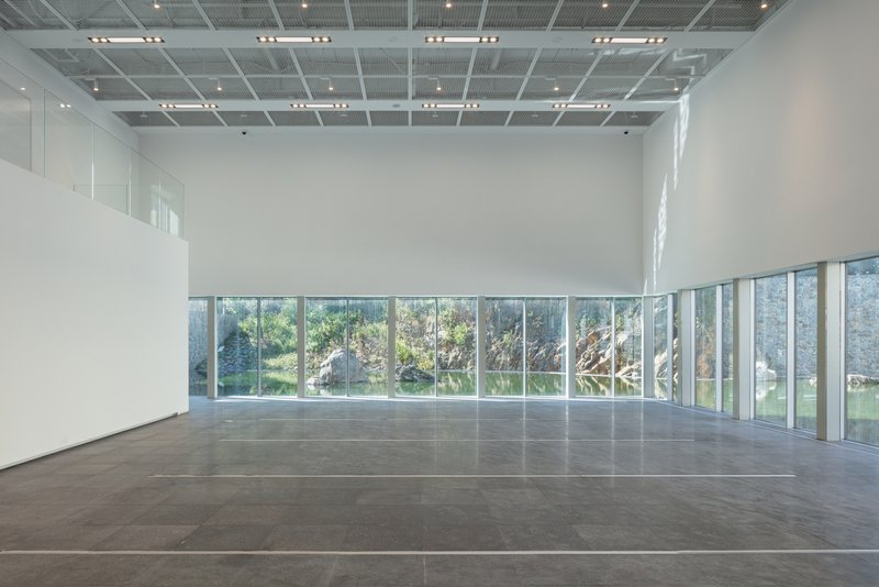 Corner gallery with full-height windows framing views of an outdoor courtyard and vegetation