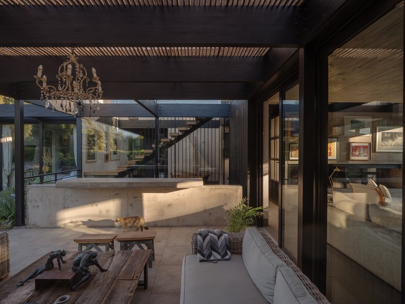 Covered terrace with curved concrete bar and timber-slatted ceiling overlooking an interior courtyard