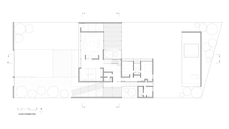 Ground floor plan drawing showing open living spaces flanked by planted courtyards on a sloped site