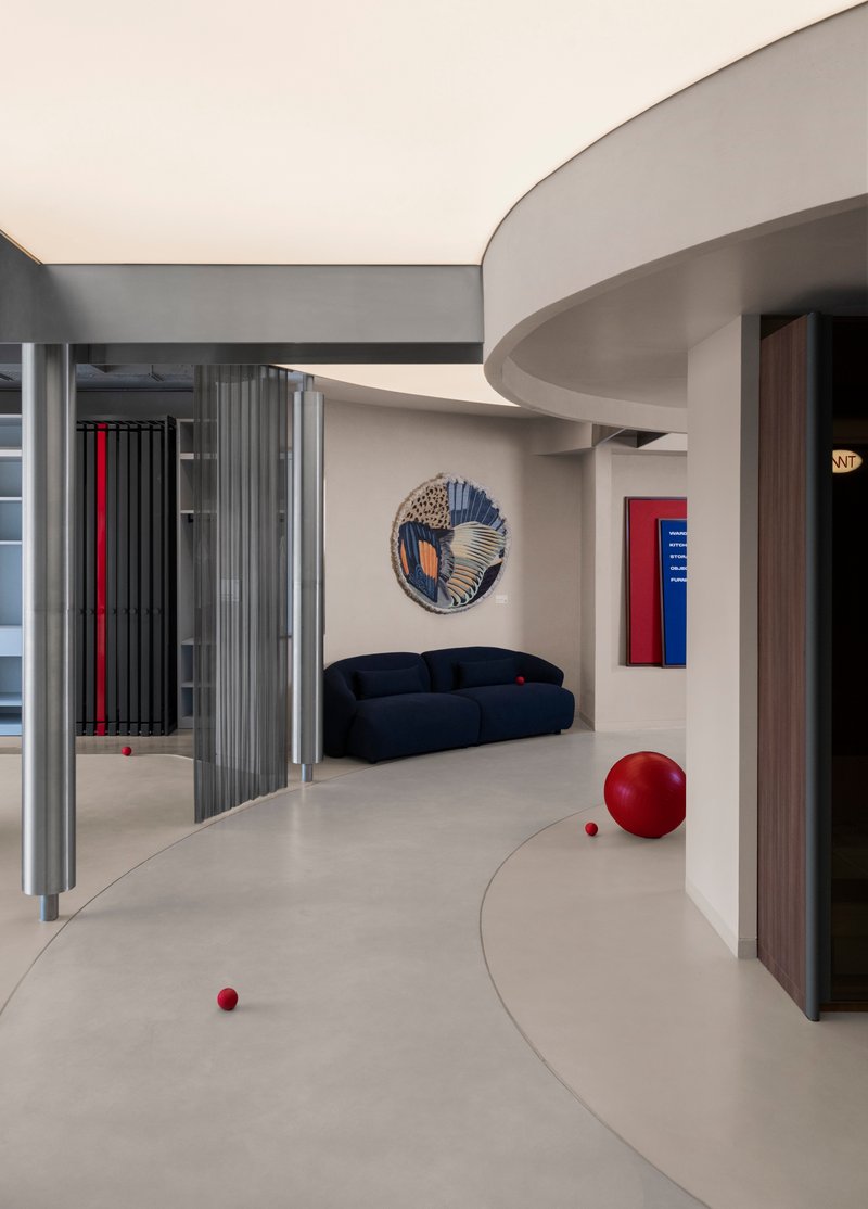 View across the polished floor showing circular wall art, a navy sofa and scattered red spheres
