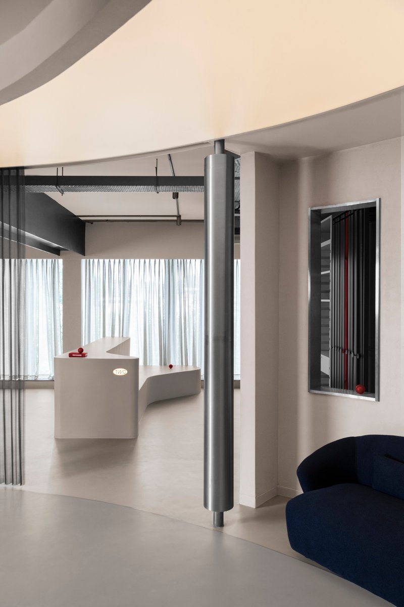 View through floor-to-ceiling ribbed screen panels with a white sheer curtain and curved soffit above