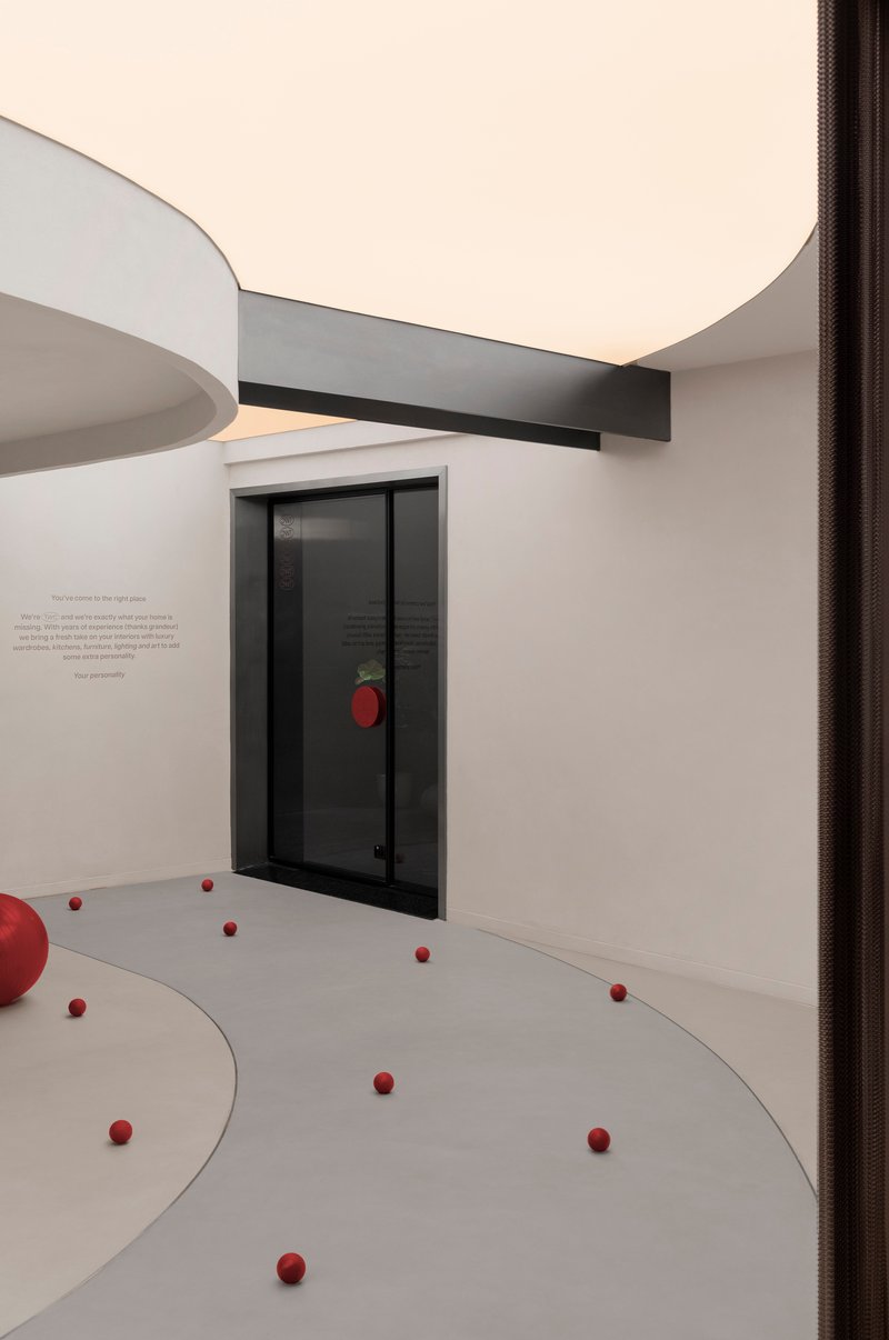 Corner view of a glazed door with red spheres arranged across the pale floor