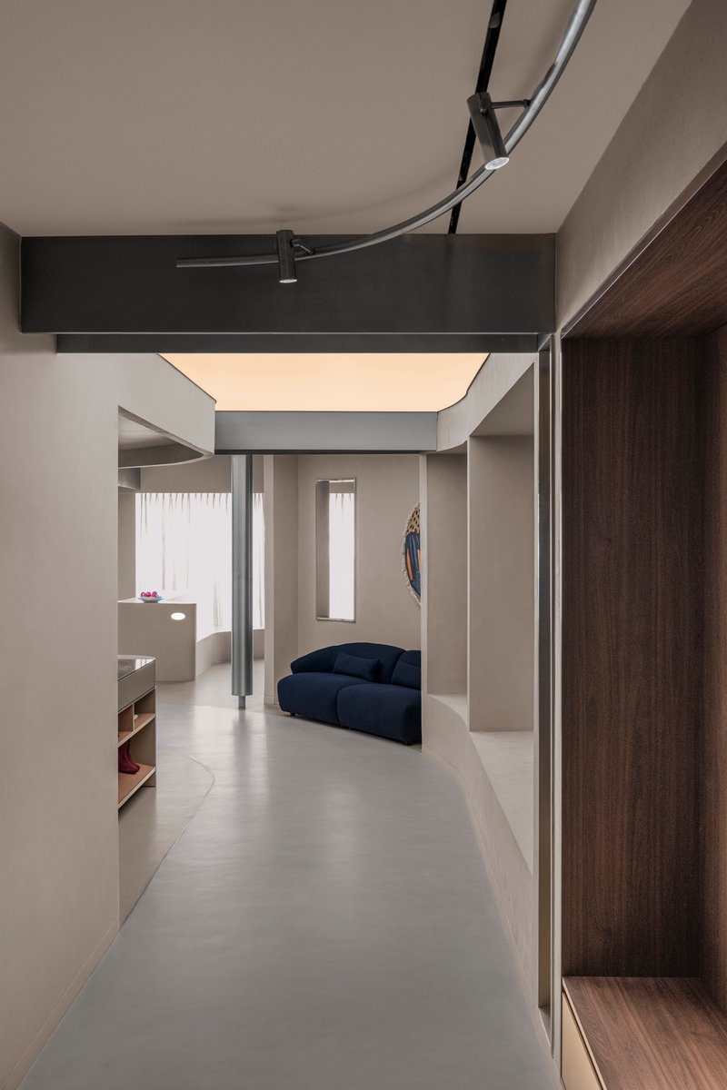 Corridor view showing recessed lighting cove above and a blue sofa in the adjacent room