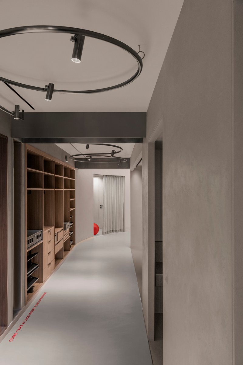 Hallway with timber storage joinery along one side and circular track lighting suspended overhead