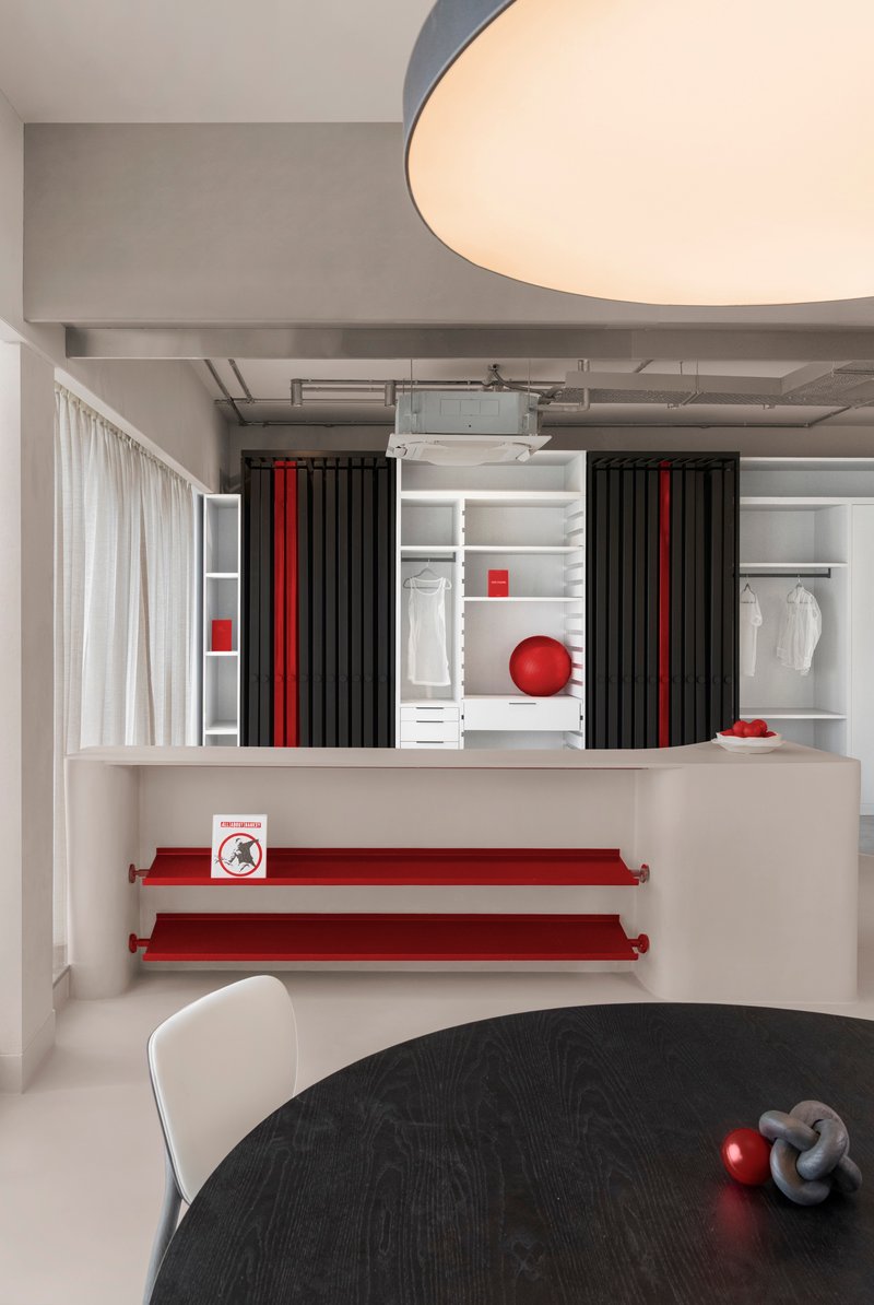 Wardrobe wall with pleated black curtains, white shelving, and red accent shelves beneath exposed ceiling ducts