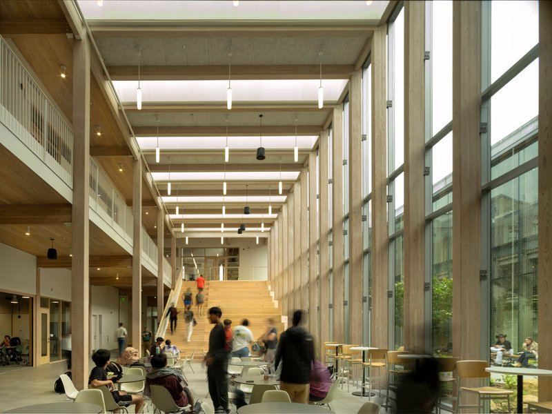 Interior atrium with exposed timber ceiling beams, wide timber staircase and students gathered below