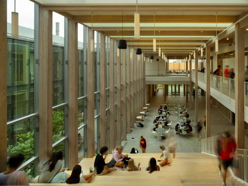 View down into double-height lobby with timber column screens and people seated along balcony edge