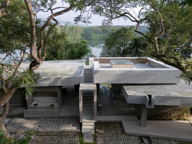Terraced concrete roof decks with central staircase overlooking a distant lake through the tree canopy