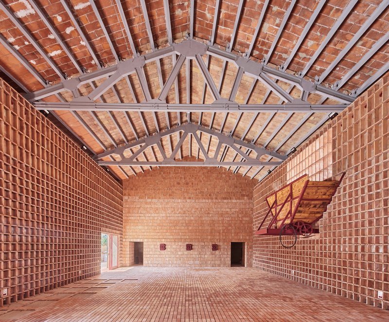 Interior hall with brick walls and vaulted tile ceiling supported by exposed grey steel trusses