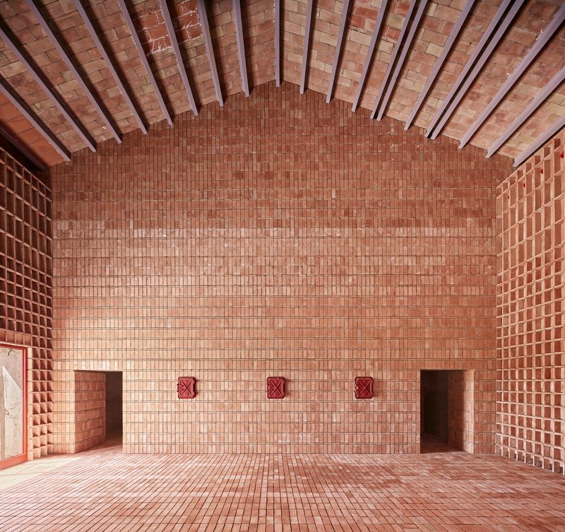 Curved brick wall with three red ventilation grilles below a vaulted tile ceiling with steel beams