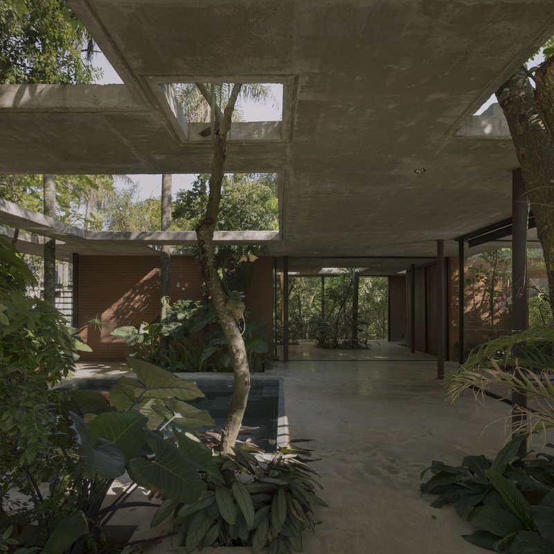 Interior courtyard with reflecting pool surrounded by concrete columns and tropical plantings beneath cantilevered slabs