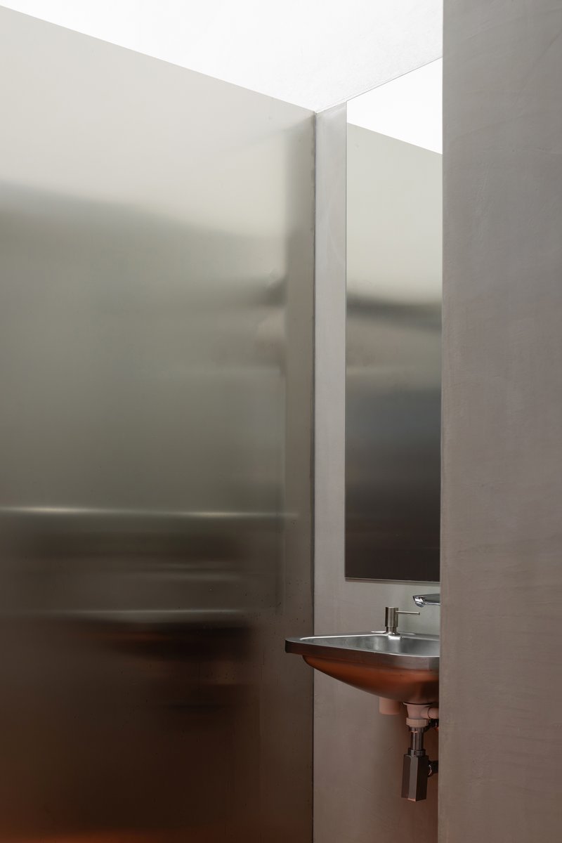 Translucent glass partition in bathroom with wall-mounted sink and vertical mirror slot