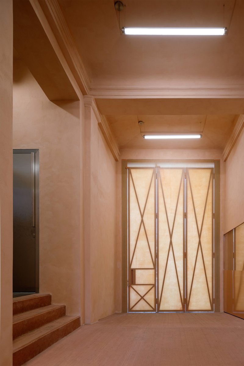 Entry hall with coffered plywood ceiling and geometric folding doors under fluorescent lighting