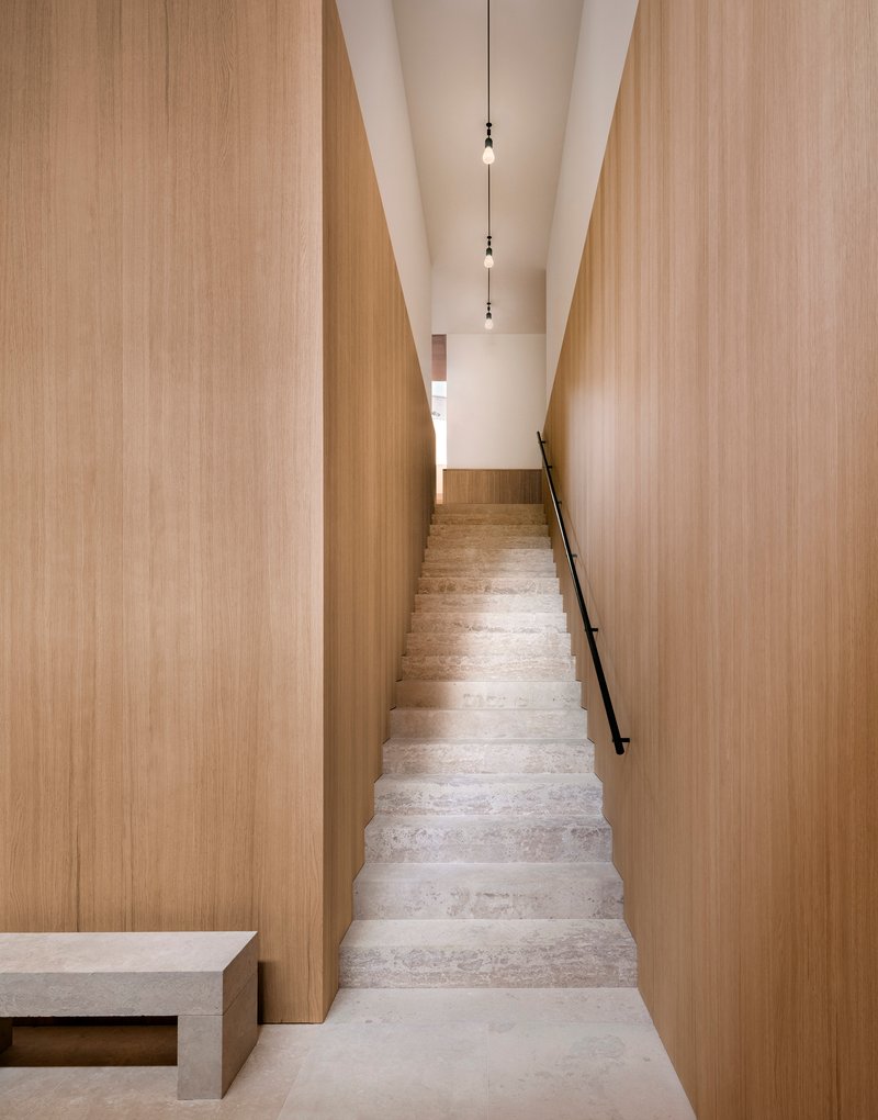 Narrow stone staircase flanked by tall timber-clad walls with pendant lights suspended from the white ceiling