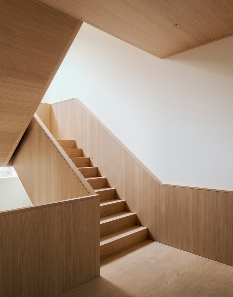 Timber-clad stairwell with light wood paneling on walls and ceiling illuminated by natural light