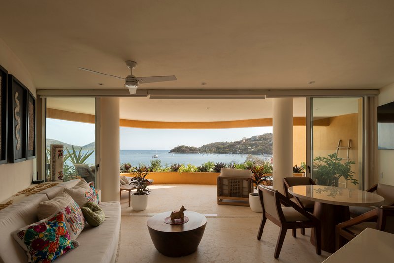 Living room opening onto a curved terrace with planted balustrade and sweeping views of the water