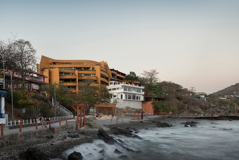 Oceanfront elevation showing stacked volumes above rocky shoreline with long exposure waves