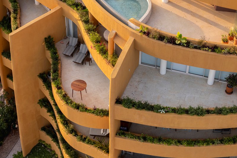 Top-down view of planted terraces wrapping around curved balconies with outdoor furniture and a pool