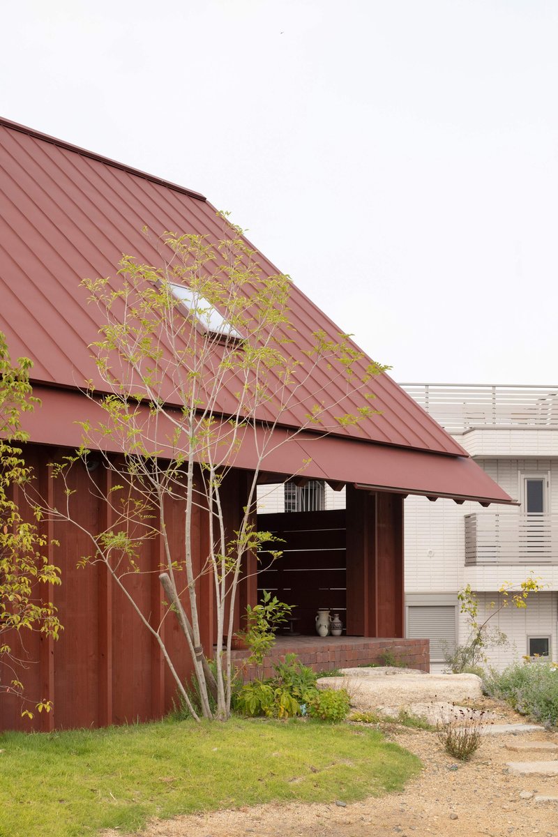 Covered entry with sloped metal roof partially screened by a young planted tree