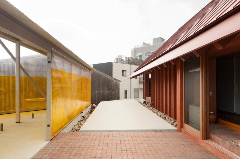 Outdoor walkway between the corrugated metal wall and yellow translucent polycarbonate screen