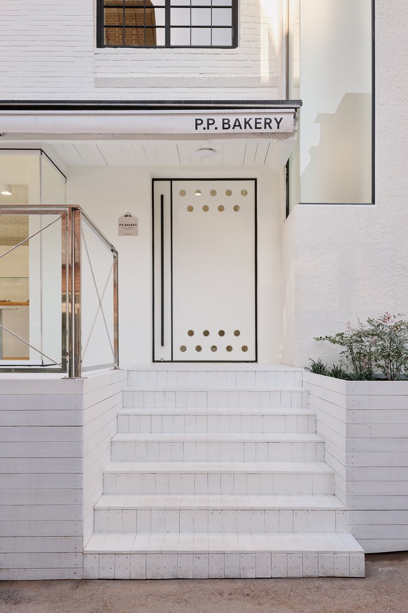 Front entrance with white tile steps and a black door with a perforated dot pattern