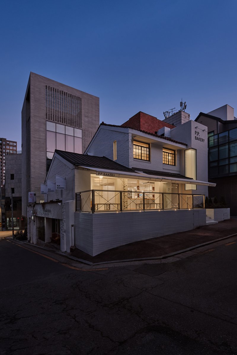 Wider street view of the bakery showing its position between taller neighbouring buildings
