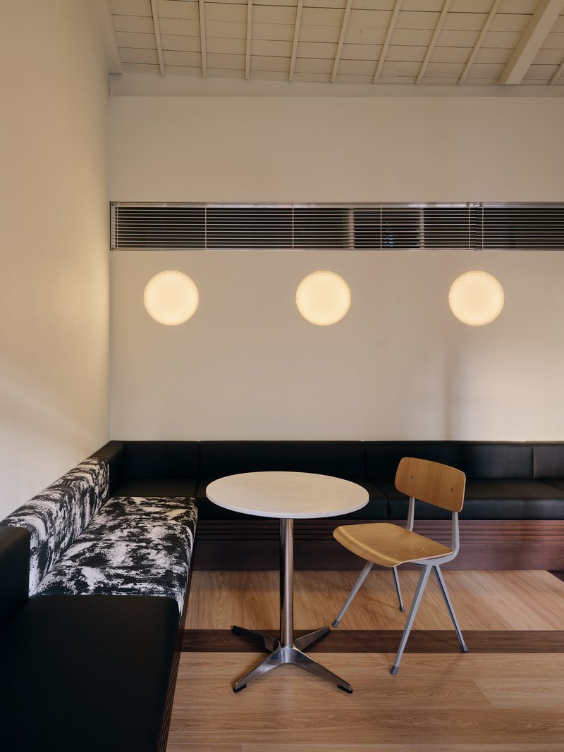Detail of a corner banquette beneath three circular sconces and a printed black-and-white seat fabric