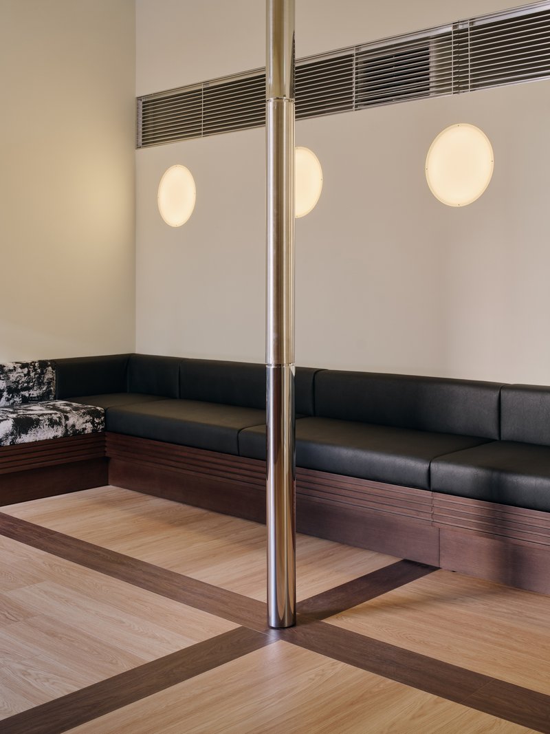 Banquette corner under three circular sconces with the steel column and timber floor border