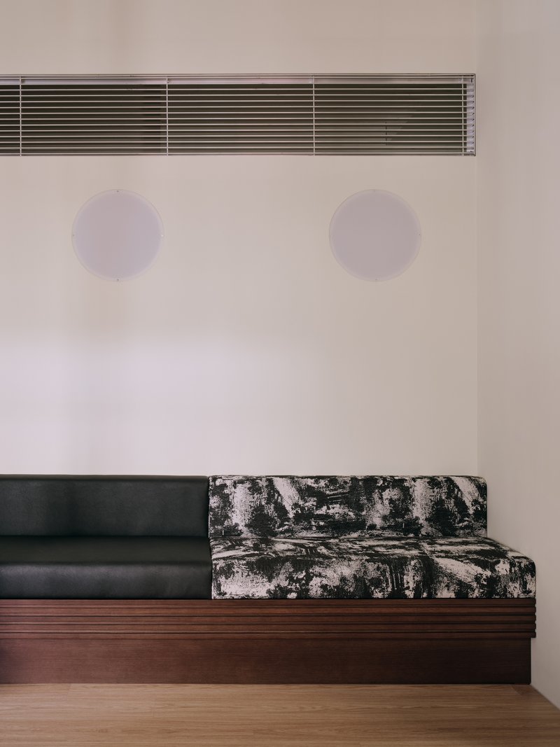 Bench detail showing the printed fabric end and two acoustic discs on the wall