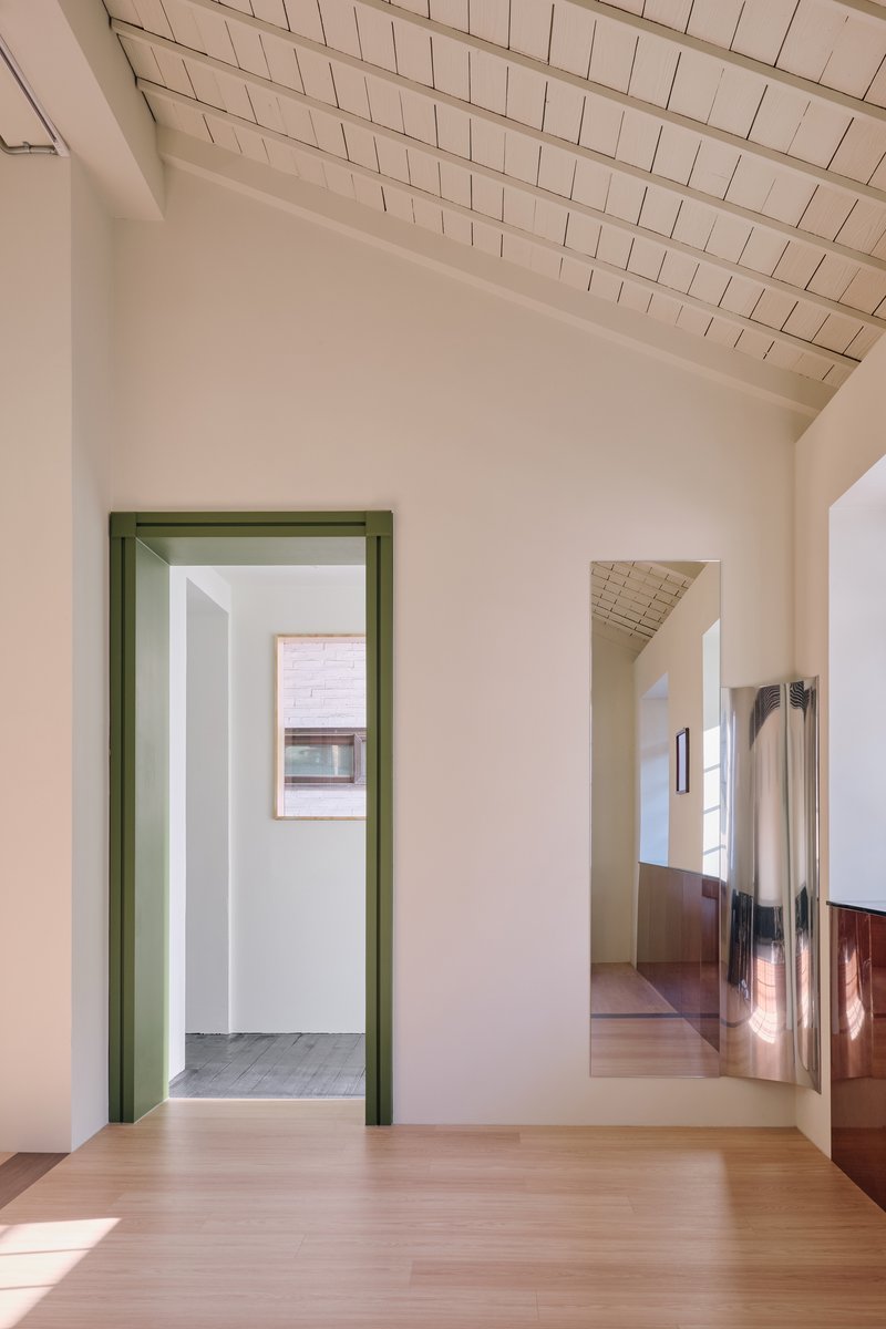 Empty corner of the upper floor with a green-framed doorway and a polished steel mirror panel