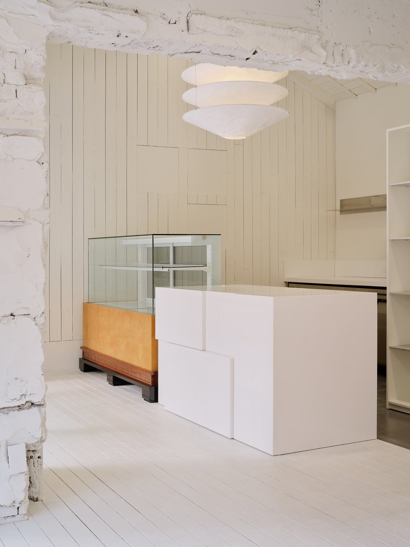 Detail of a glass display cabinet on a wooden base beside a stepped white counter