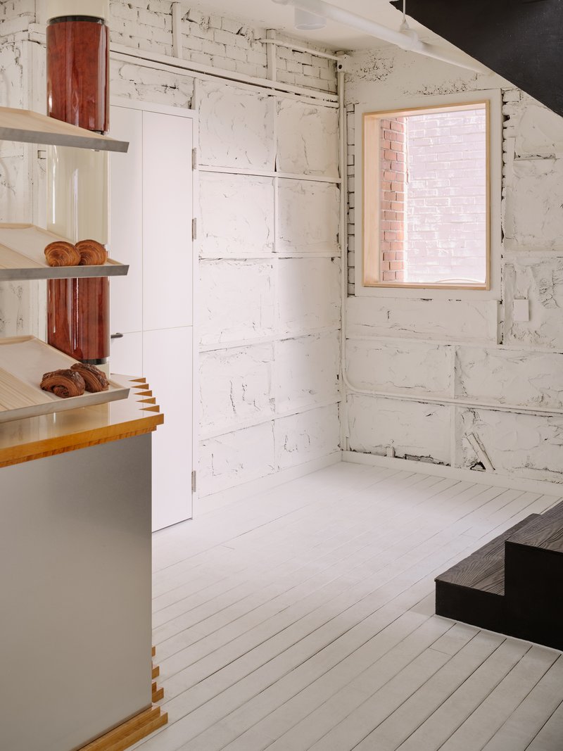 Side view showing a punched window in the rough white plaster wall and the bakery counter