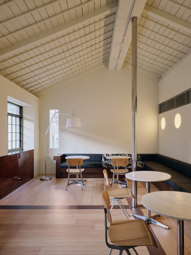 Upper floor cafe with the original tiled vaulted ceiling and a row of black benches along the wall