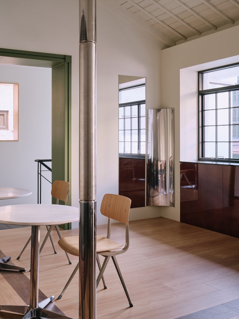 Upper-floor corner with two windows above a glossy maroon dado and a polished steel column