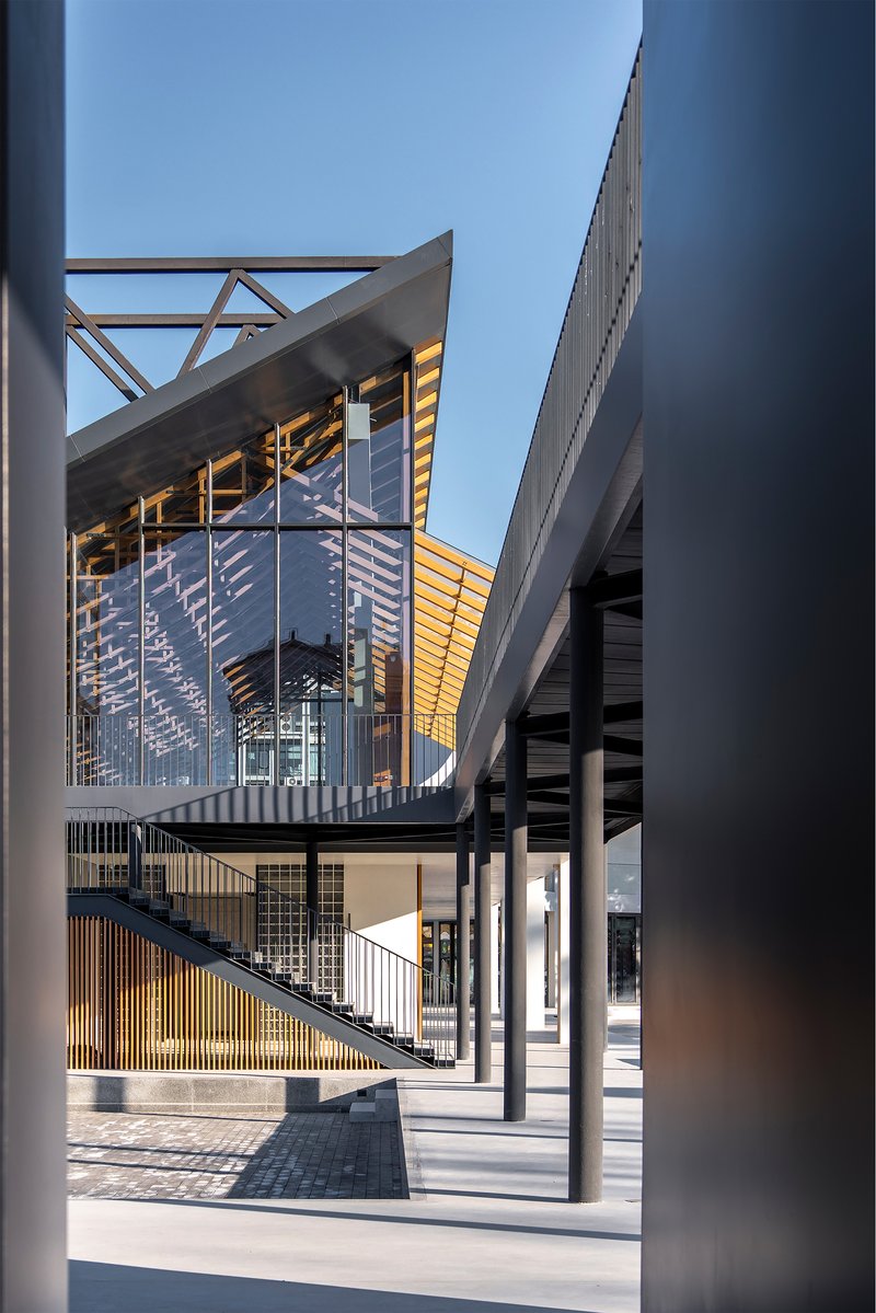 Framed view through white columns showing exterior steel staircase and timber screening at dusk