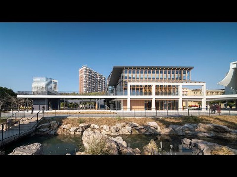 Front elevation showing the glazed facade and elevated roof canopy above a water feature with rocks