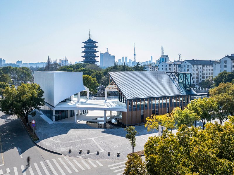 Aerial view of two volumes with sloped metal roofs facing a plaza with pedestrian crossings