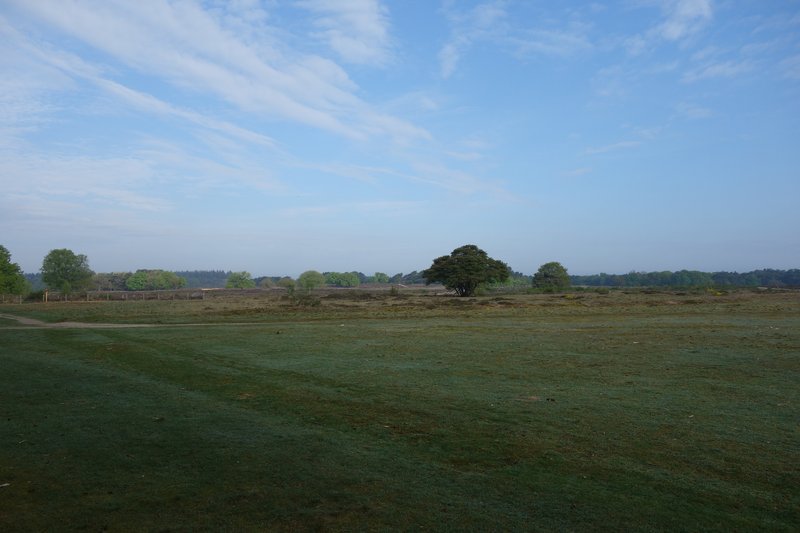 Low timber-clad structure set in an open heath landscape under partly cloudy sky