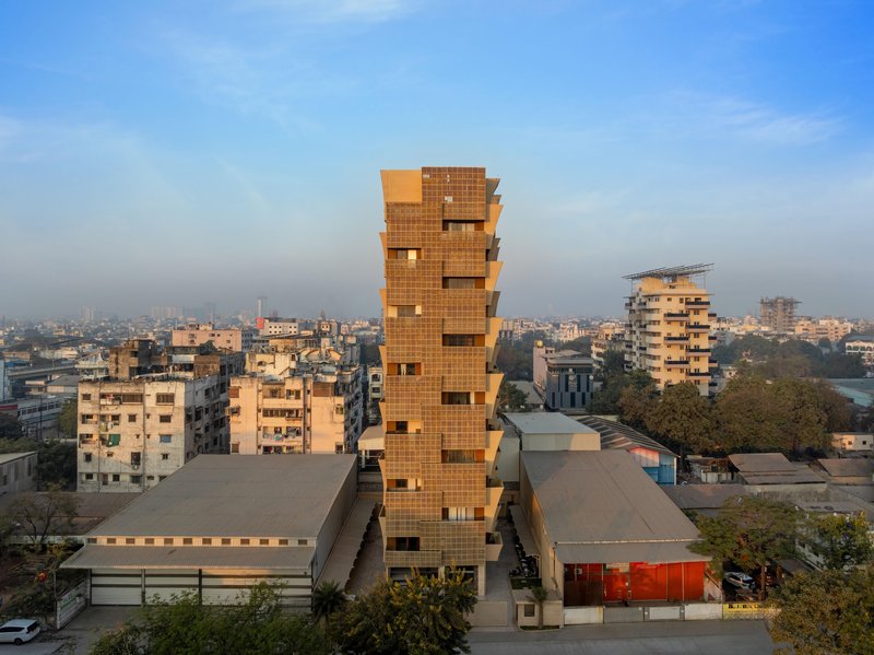 Stacked brick tower rising above a dense urban neighborhood at dusk
