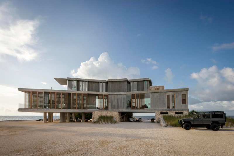 Beach approach showing the stacked concrete and timber volumes with central carport and parked vehicle