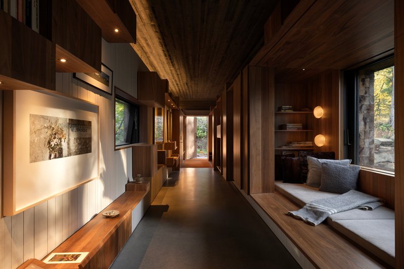 Corridor with built-in window seat and timber-lined ceiling leading to exterior views