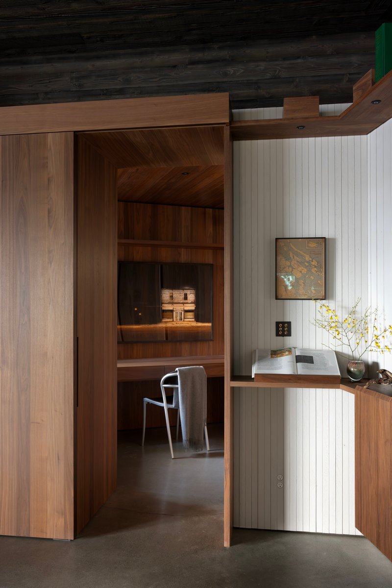 Timber-framed doorway opening into office niche with built-in desk and shelving