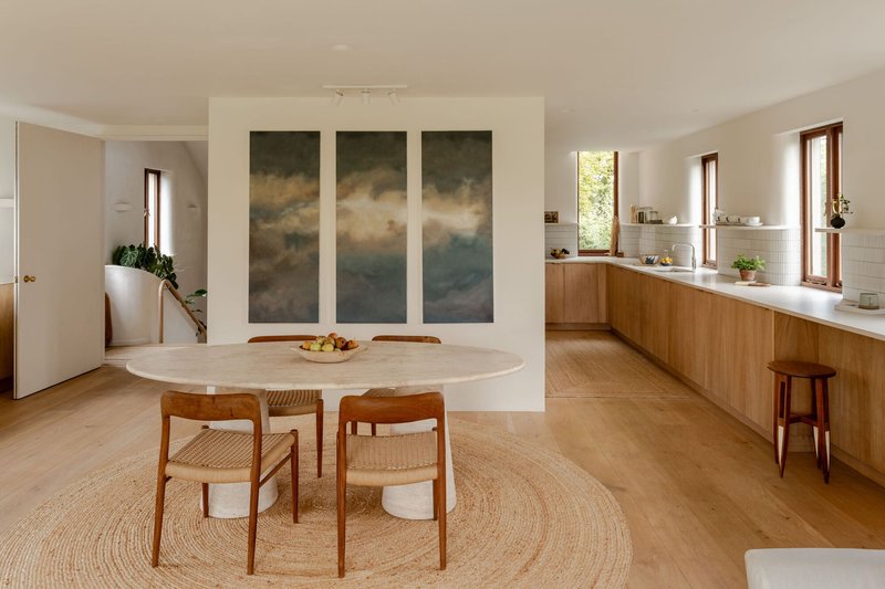 Dining area with timber kitchen joinery and triptych artwork on white wall
