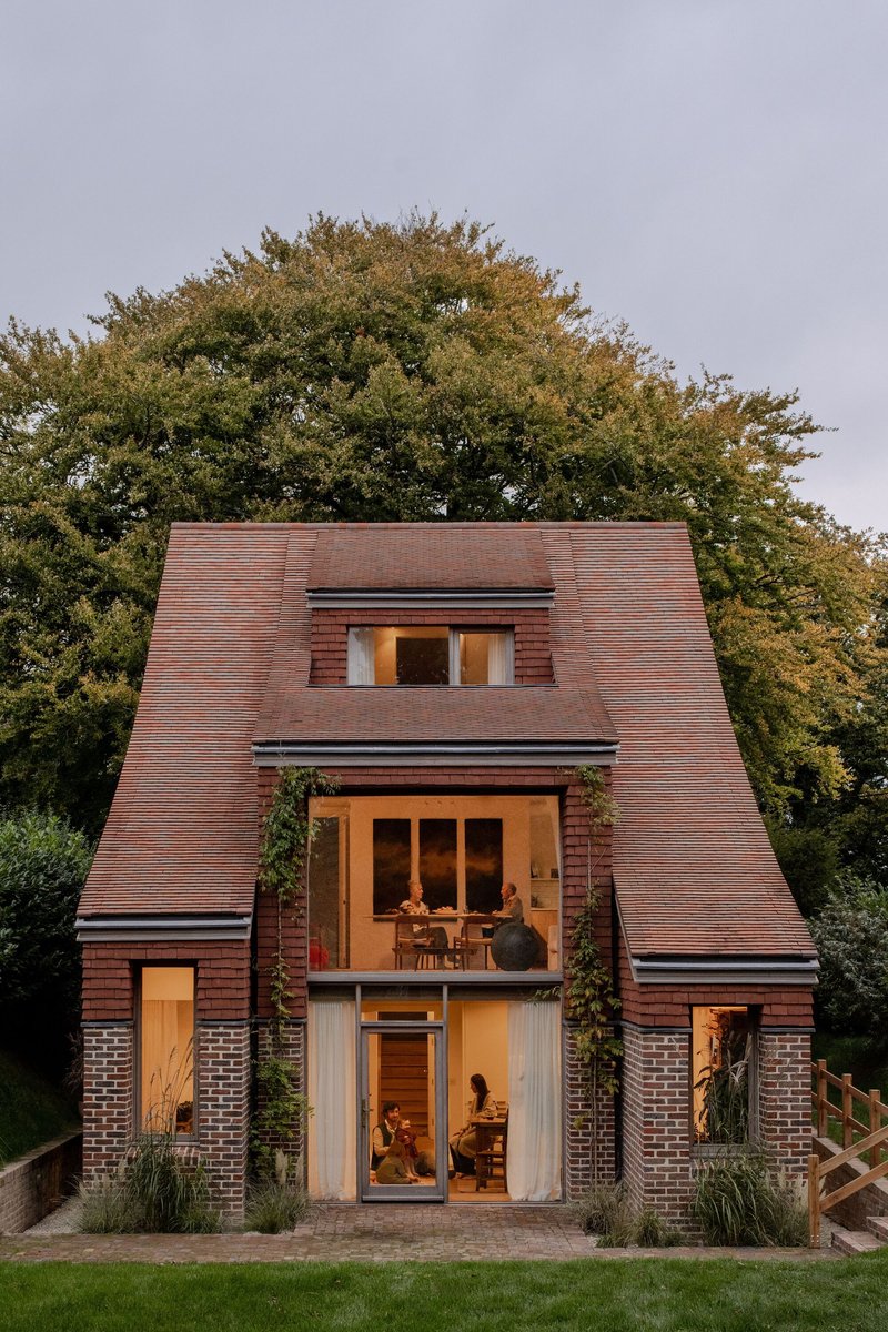 Front elevation showing stacked glazed openings and inhabitants visible inside at twilight