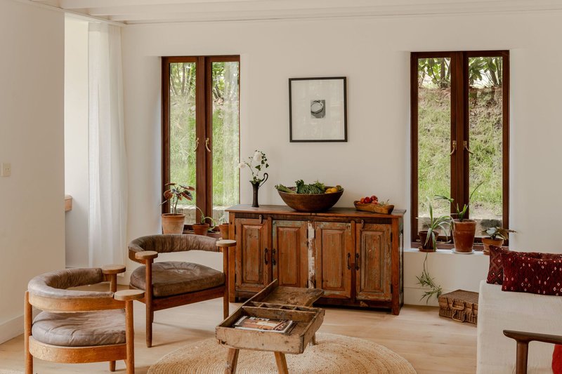 Sitting area with antique cabinet and paired timber casement doors framing views of native grasses outside