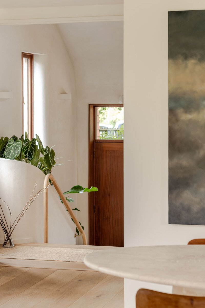 Timber-framed doorway with glazed upper panel framed by white walls and potted plants