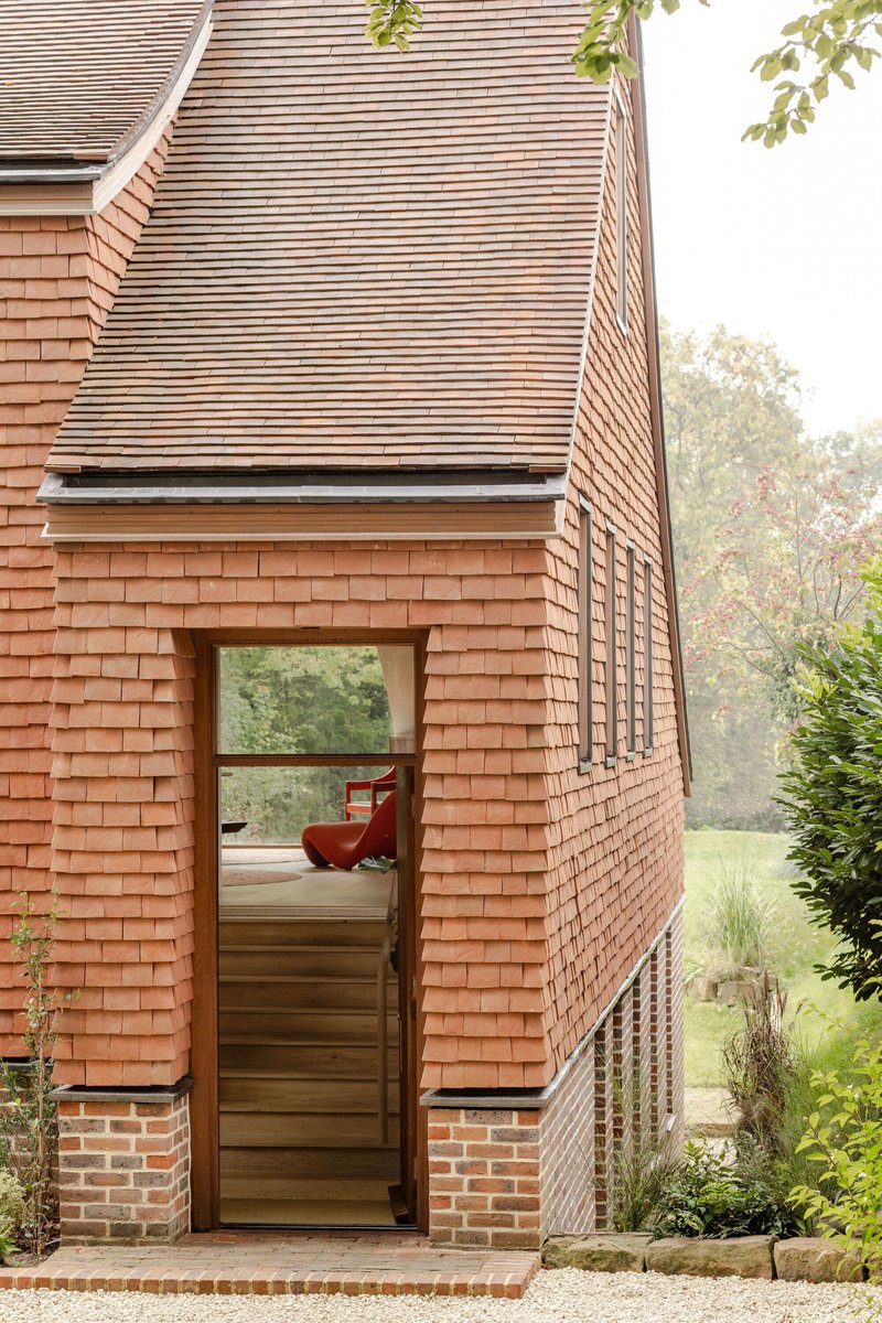 Entrance detail showing glazed door on brick plinth beneath horizontally-tiled upper volumes