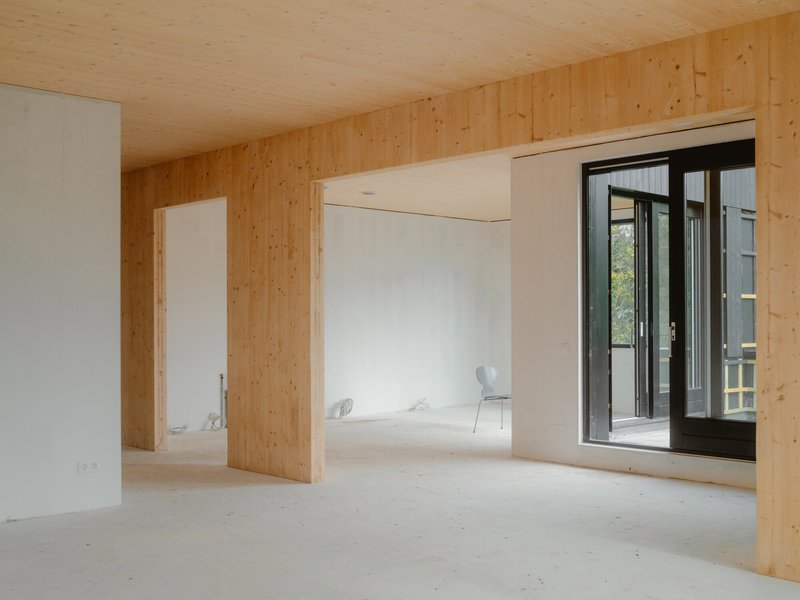 Unfurnished interior room with exposed plywood walls and ceiling opening to a small balcony
