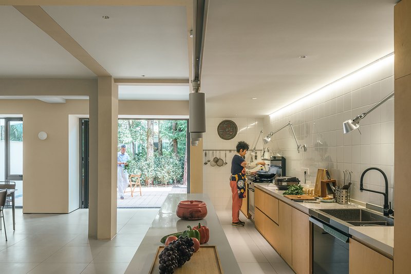 Open kitchen with timber cabinetry and white tile backsplash as someone prepares food